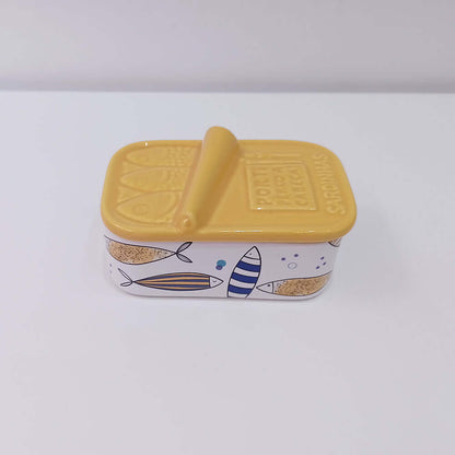 Caixa de cerâmica amarela em formato de lata de sardinha com peixes desenhados.